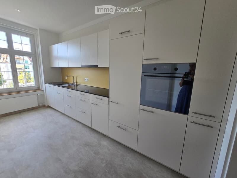 Modern kitchen with white cabinets, stainless steel sink, and built-in oven. Features a sleek design with ample storage space and a clean, contemporary aesthetic.