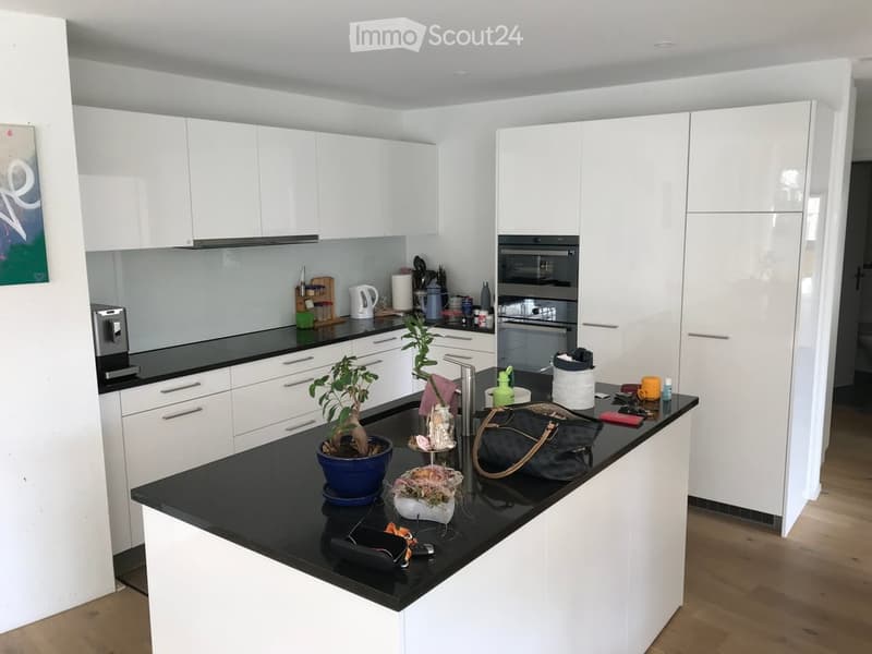 Modern kitchen with white cabinets, black countertop, and various appliances and items on the counter.