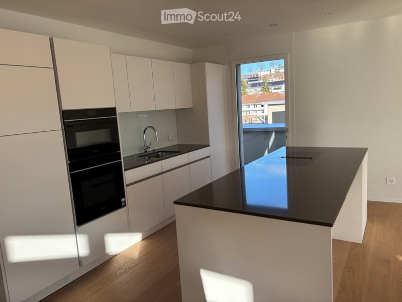 Modern kitchen with white cabinets, black countertops, a sink with a modern faucet, and an integrated oven. Large window offers a view of the city.