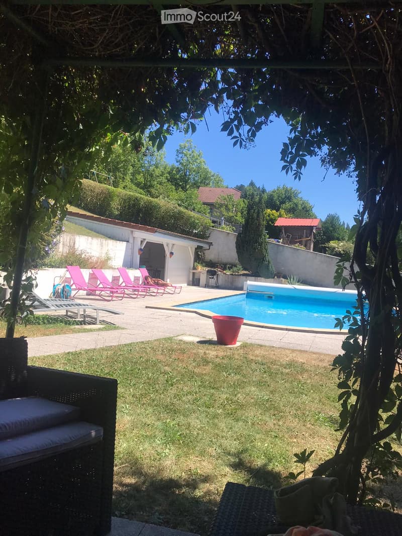 Garden with a swimming pool, lounge chairs, and a grassy area.