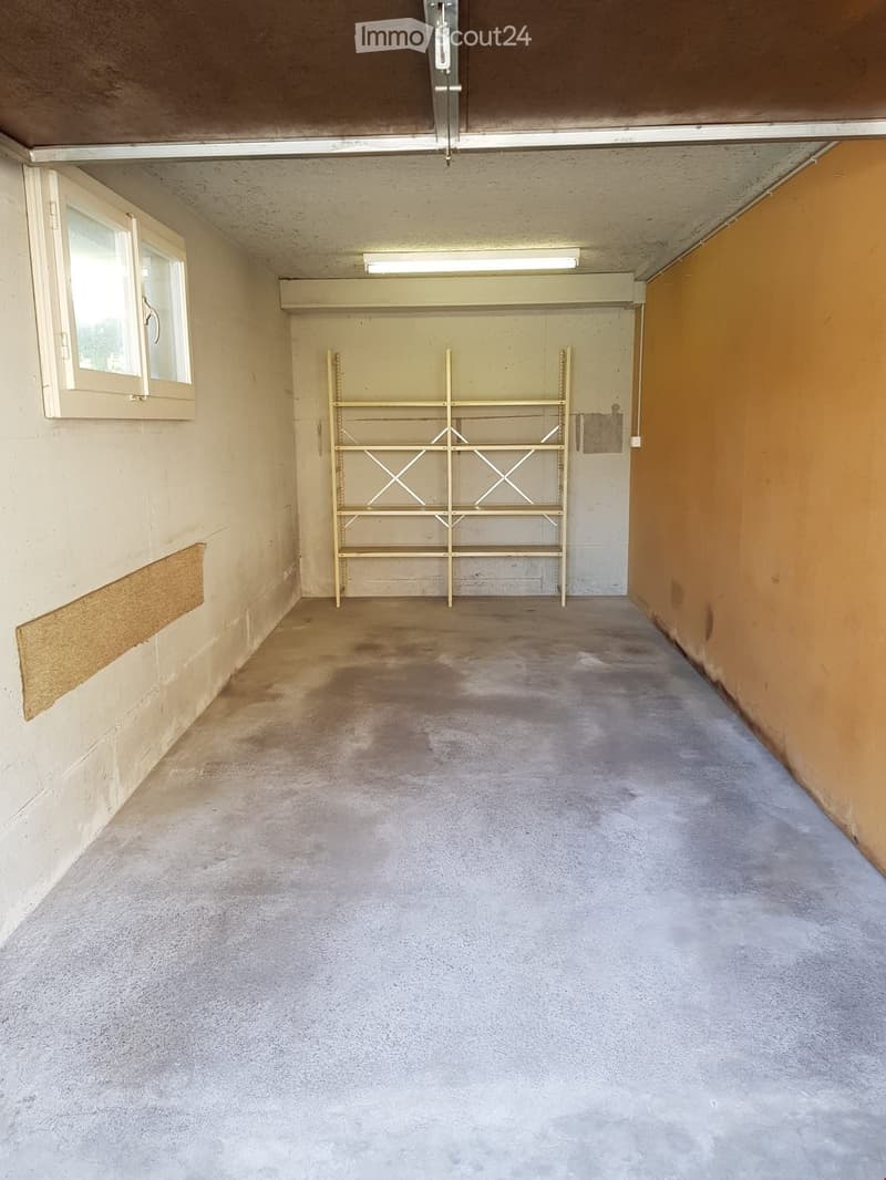 Empty room with concrete floor, white walls, and a single window on the left side. A metal shelving unit is positioned against the back wall.