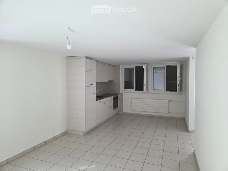 Modern kitchen with white cabinets, tiled floor, and large windows. Features an oven and radiator.