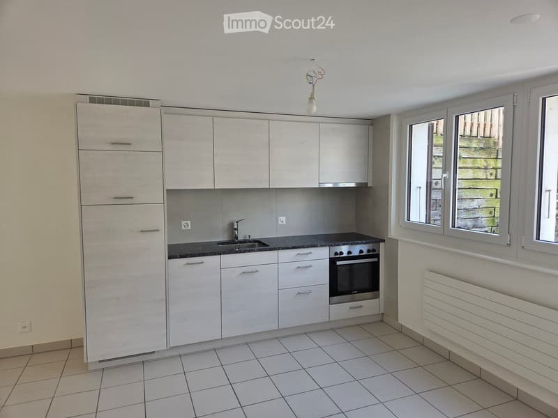 Modern kitchen with white cabinets, tiled floor, and stainless steel appliances including a sink and oven.