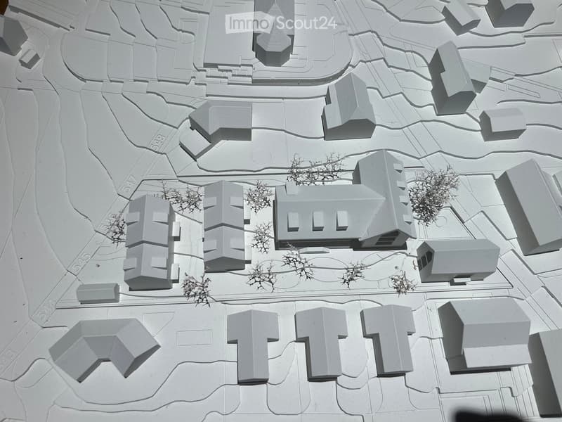 3D model of a building complex with multiple structures, pathways, and small clusters of trees.