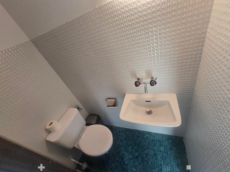 Modern bathroom with white toilet, sink, and patterned tiles on walls and floor.