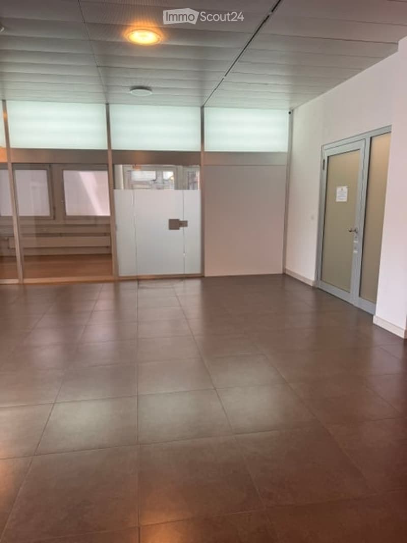 Empty room with tiled floor, white walls, and large windows. No furniture or equipment present.