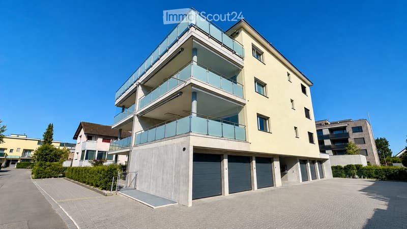 Modern multi-story building with balconies and a garage entrance.