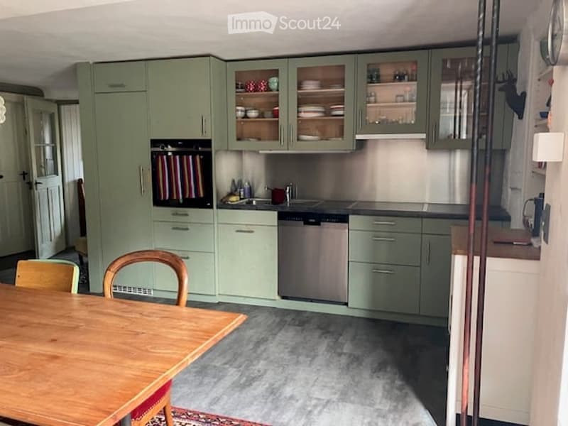 Kitchen. A modern kitchen with mint green cabinets, stainless steel appliances, and a wooden dining table with chairs.