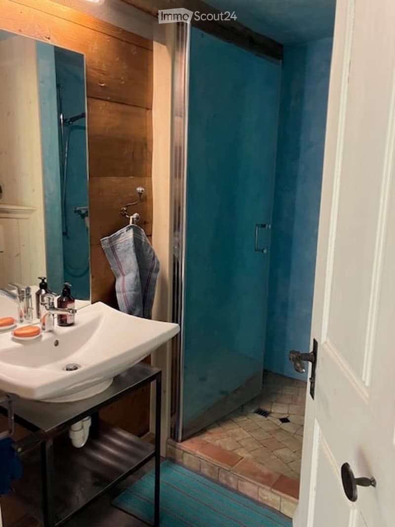 Bathroom. Modern bathroom with a white sink, chrome faucet, mirror, glass shower enclosure, and a towel hanging on a rack.
