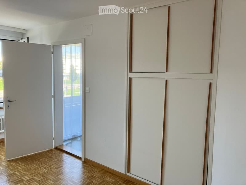 Empty room with wooden flooring, white walls, and a glass door leading to an outdoor area.