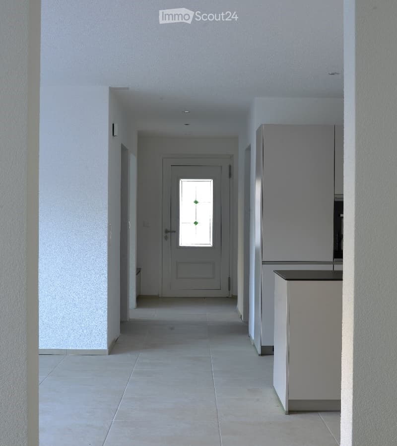 Clean, modern hallway with white walls, tiled floor, and a door at the end featuring a decorative glass panel.