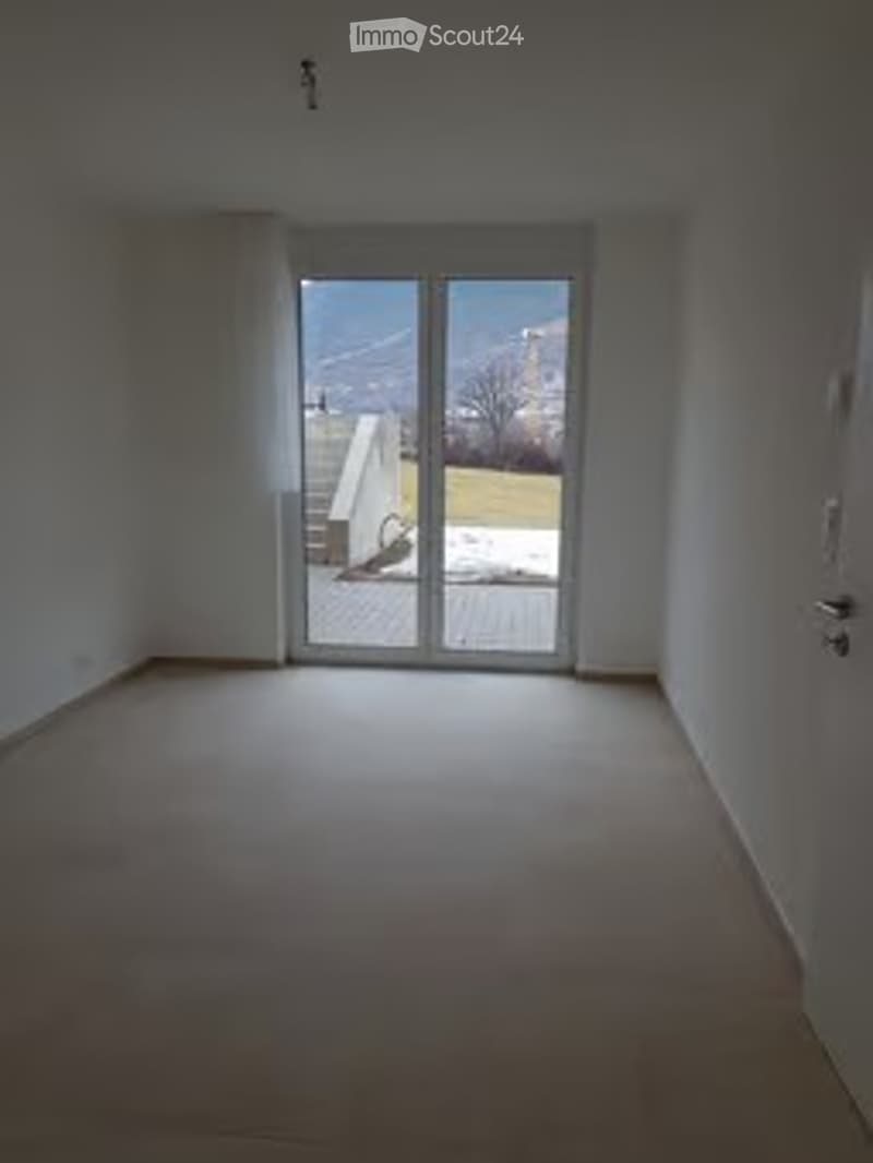 Empty room with large sliding glass doors leading to a balcony, white walls, and a carpeted floor.