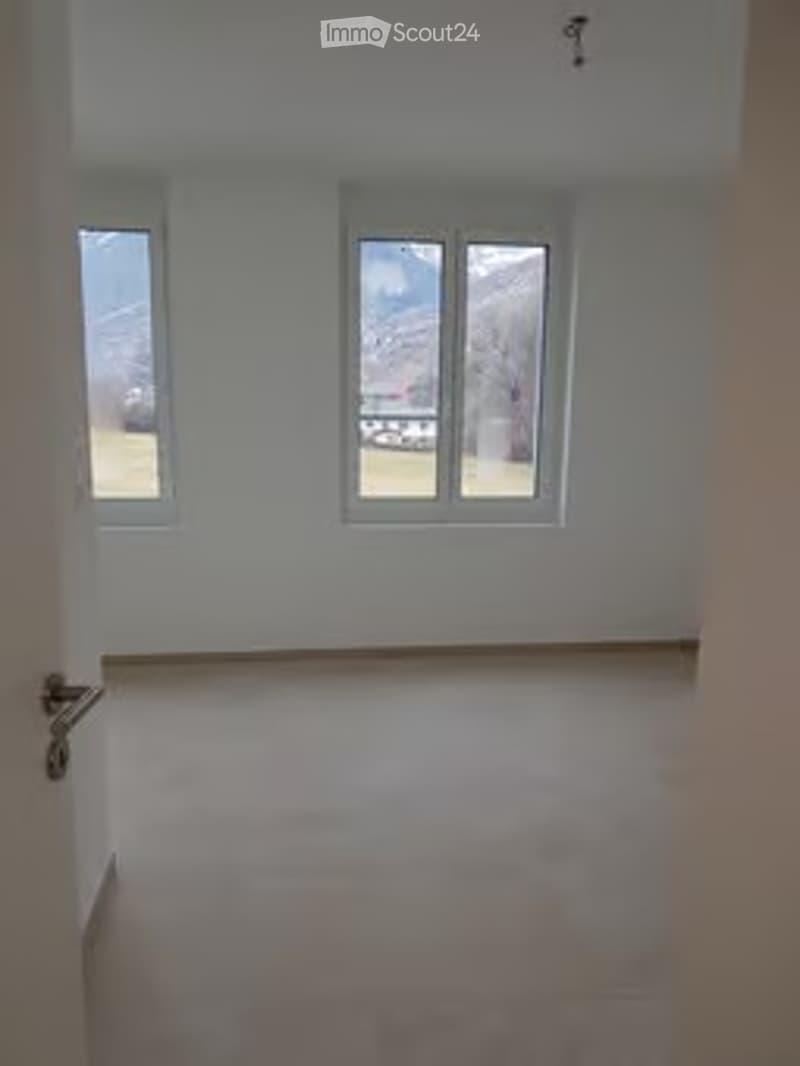 Empty room with white walls, large windows, and a wooden floor. No furniture or equipment present.