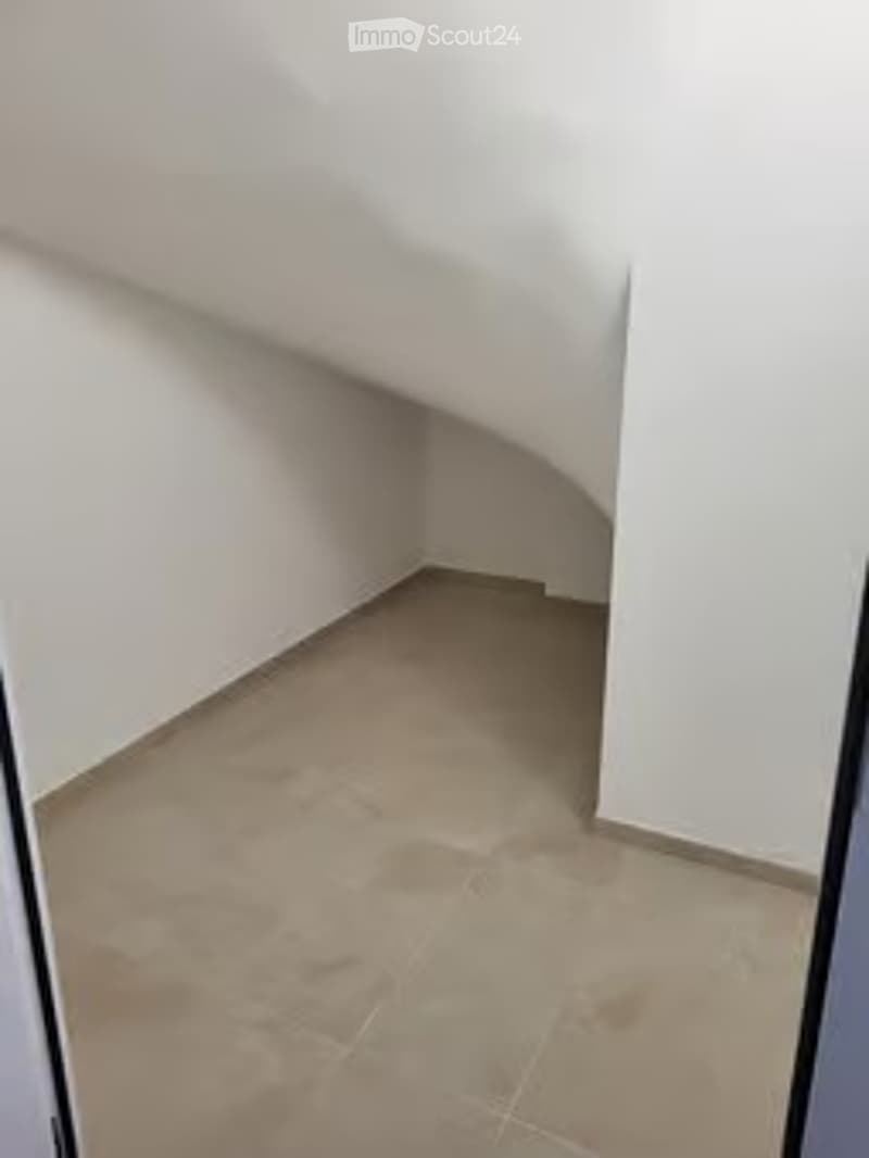 Completely empty room with white walls and beige tiled floor. No furniture or equipment.