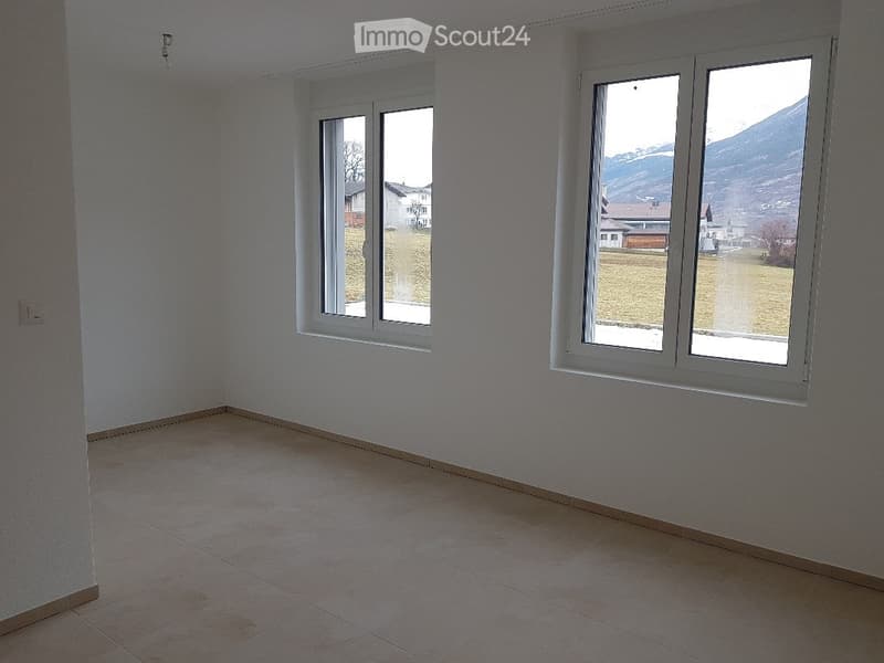 Empty room with white walls, tiled floor, and large windows offering a view of the countryside.