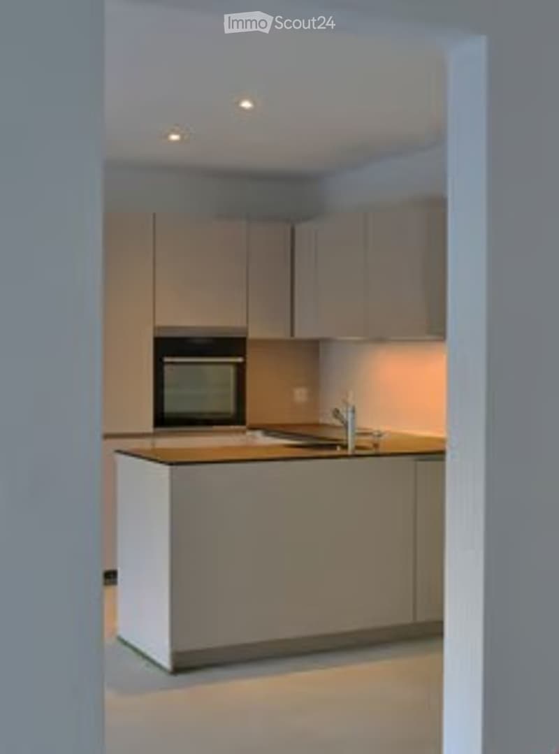 Modern kitchen with light-colored cabinets, a central island, and a sink with a faucet. An oven is integrated into the cabinetry.