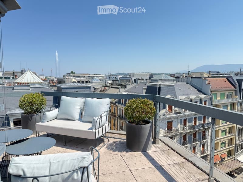 A modern rooftop terrace with a white sofa, two side tables, a chair, and potted plants, overlooking a cityscape with rooftops and a fountain.