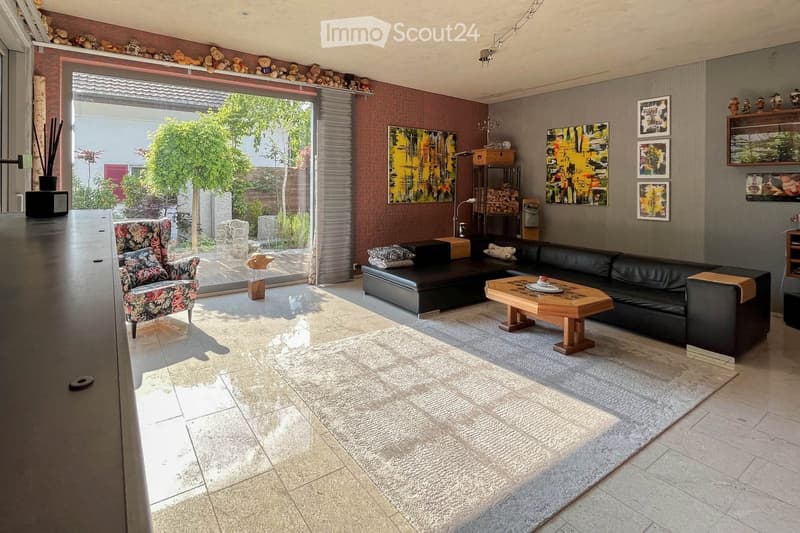 open floor plan, black leather sectional sofa, glass doors to patio, wooden coffee table, rugs, artwork on wall, decorative items