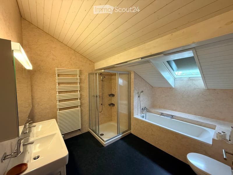 Modern bathroom with a sink, bathtub, toilet, shower, radiator, and a skylight window above the bathtub.
