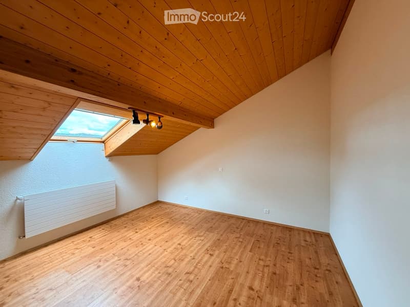 Empty room with wooden flooring, white walls, and a skylight window. Features a white radiator and recessed lighting.