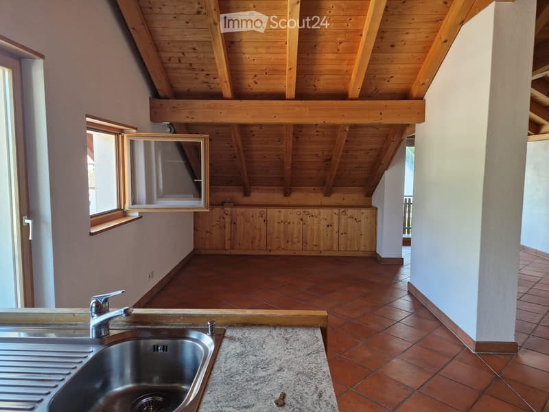 Bright kitchen with wooden ceiling beams, granite countertop, stainless steel sink, and wooden cabinets.