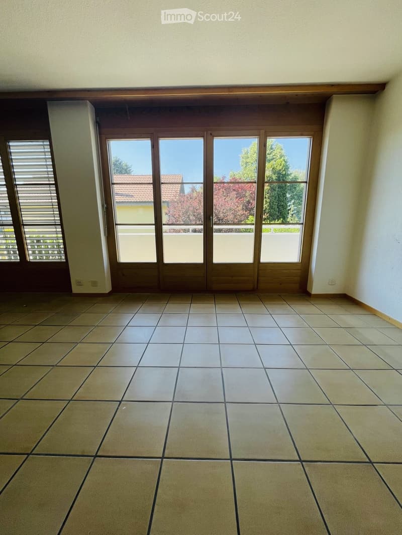 Empty room with tiled floor, large sliding glass doors, and a window with blinds on the left side.
