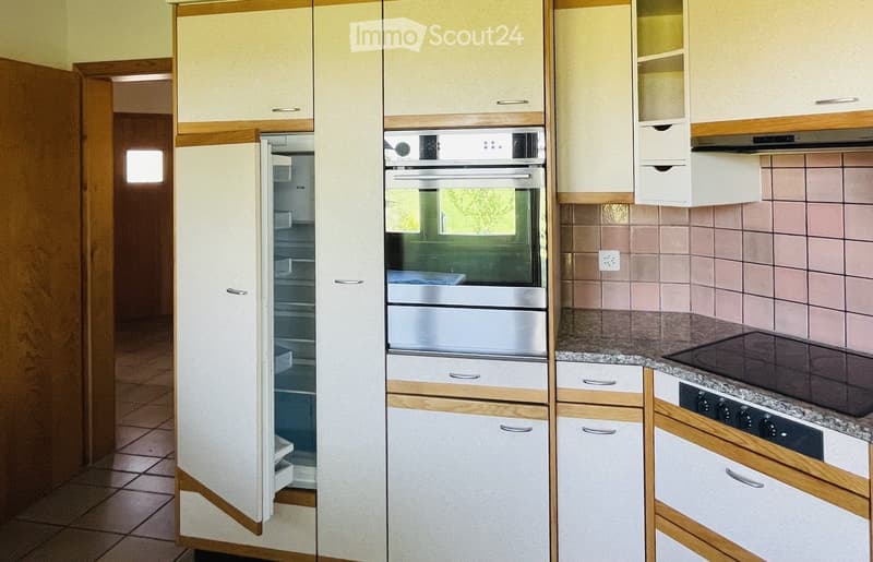 Modern kitchen with light-colored cabinets, stainless steel appliances including a refrigerator, oven, and stove, and granite countertops.