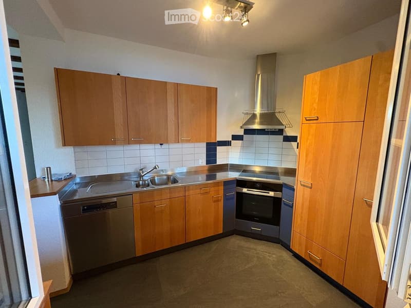 Modern kitchen with wooden cabinets, stainless steel sink, oven, and dishwasher. The space features a tiled backsplash and recessed lighting.