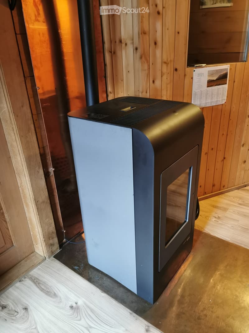 Modern electric fireplace with sleek design, placed on a wooden floor in a room with wooden walls and a calendar visible in the background.
