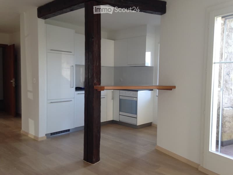 modern kitchen with white cabinets, wooden floor, white appliances, wooden beam