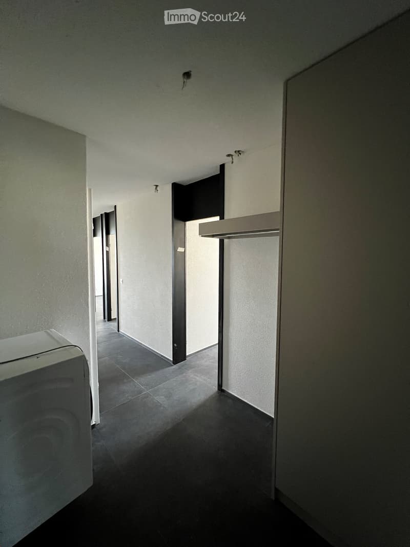 Modern hallway with dark tiled floor, white walls, and several doors leading to other rooms.