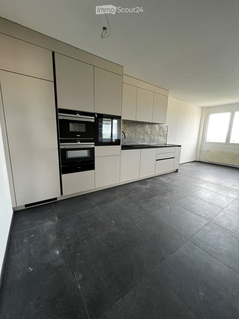 Empty kitchen with white cabinets, black oven, and dark tiled floor.
