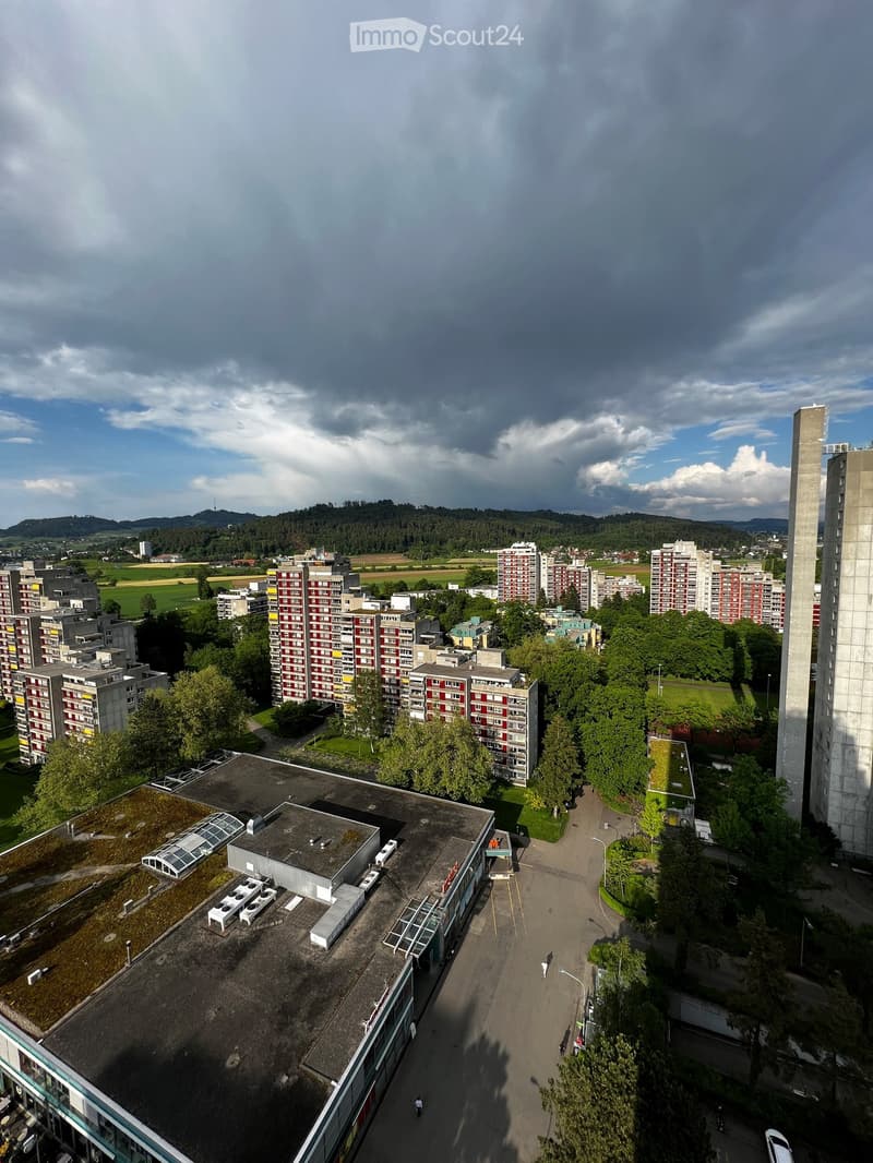 Aerial view of a residential area with multiple apartment buildings, green spaces, and a parking lot.