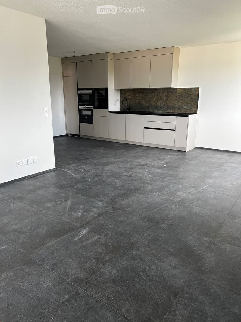 Empty kitchen with white cabinets, dark tiled floor, and built-in appliances including an oven and sink.