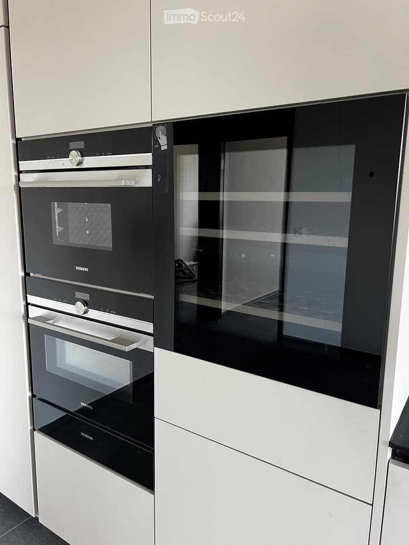 Modern kitchen with sleek, built-in Siemens ovens featuring stainless steel and black finishes, integrated into white cabinetry.