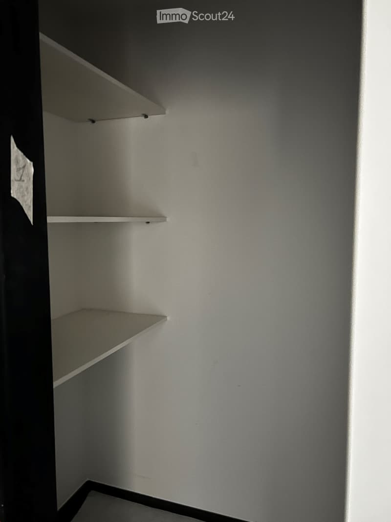 Empty corner closet with three white shelves and a smooth, light-colored wall.