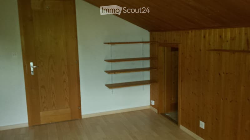 Empty room with wooden floor, white walls, and built-in wooden shelves. No furniture or equipment present.