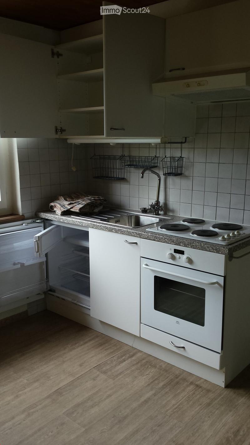 Modern kitchen with white cabinets, granite countertop, stainless steel sink, electric stove, and refrigerator. Wooden flooring and tiled backsplash.