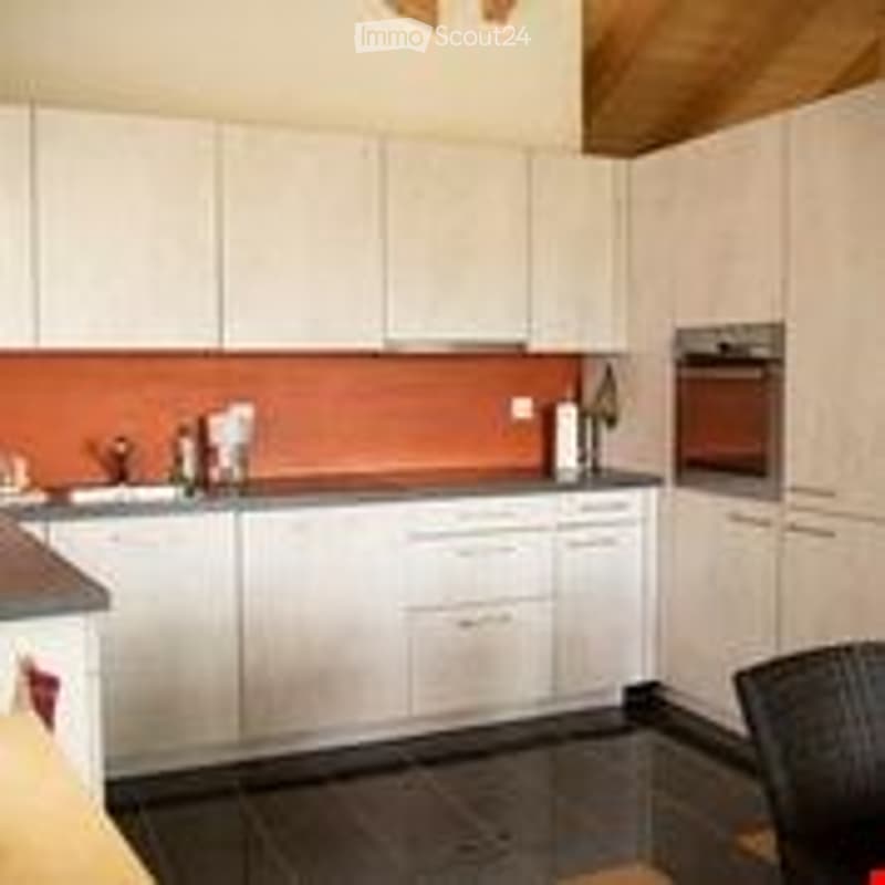 Modern kitchen with white cabinets, dark countertop, and stainless steel appliances.