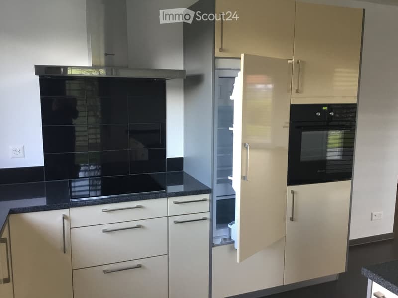 Modern kitchen with white cabinets, stainless steel appliances, and a black countertop.