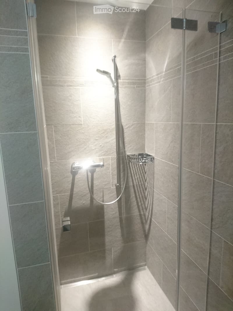 shower room with tiled walls, shower head and hand held shower, floor-level shower tray, shower cabin