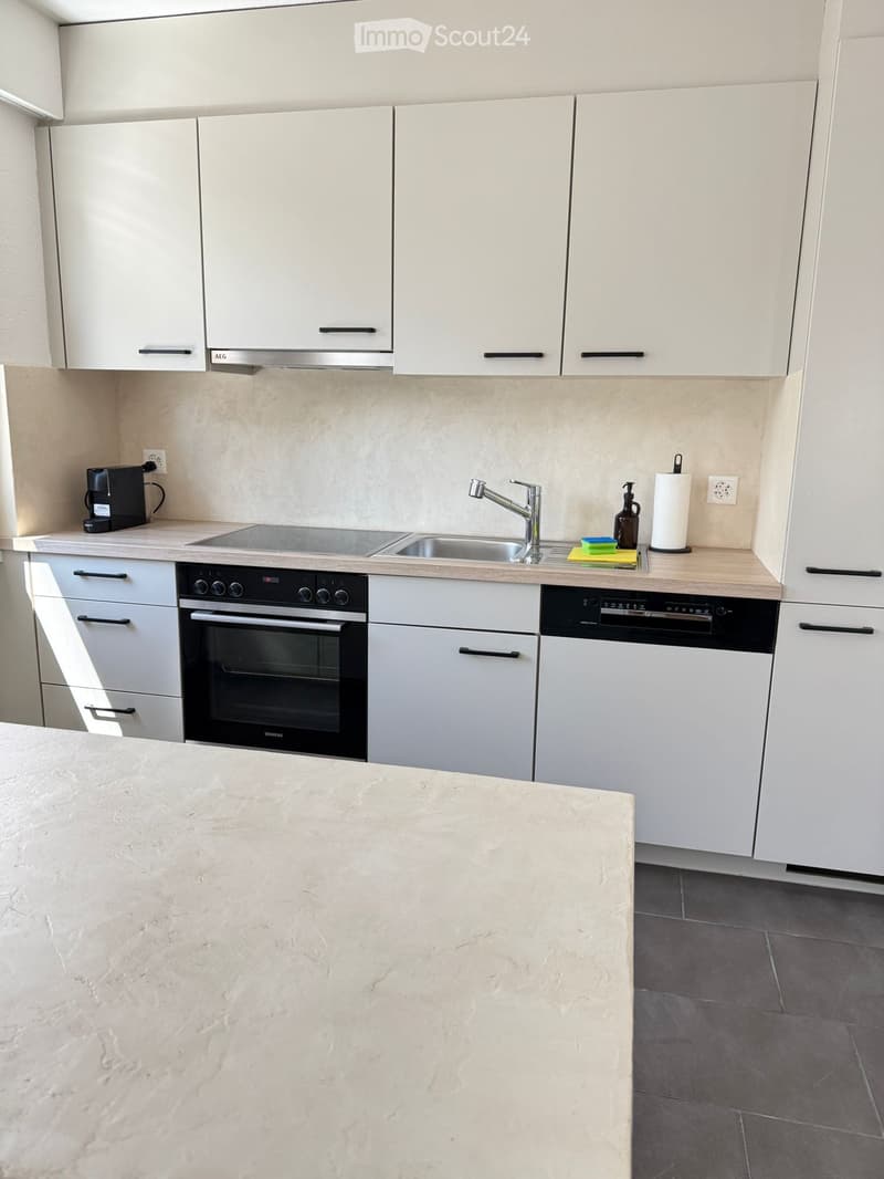 Modern kitchen with white cabinets, stainless steel appliances, a large island, and a sink with a modern faucet.