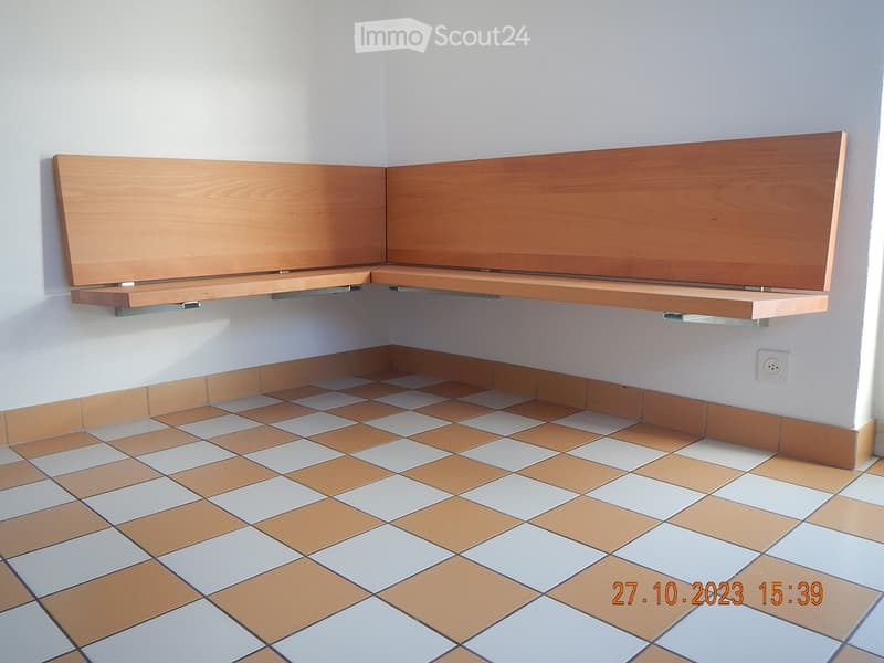 Empty room with tiled floor and built-in wooden bench seating along the wall.