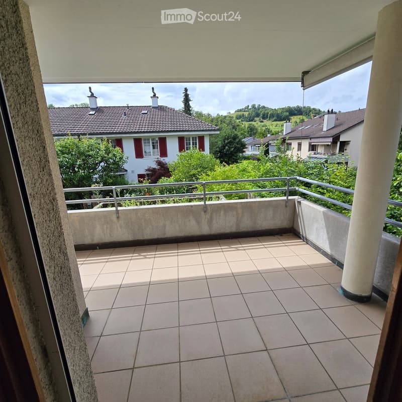 Balcony with tiled floor, metal railing, and scenic view of houses and greenery.