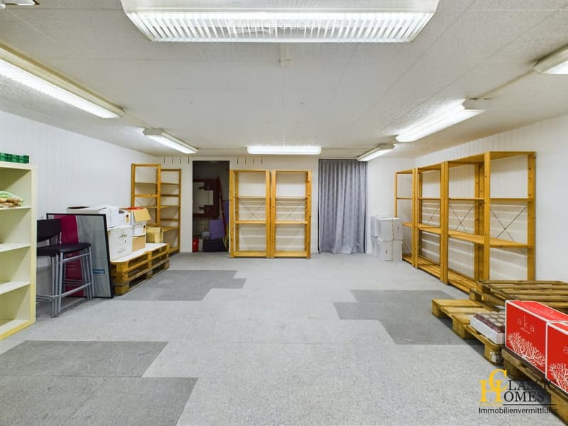 Empty room with white walls, grey carpeted floor, and wooden shelving units. No furniture or equipment present.