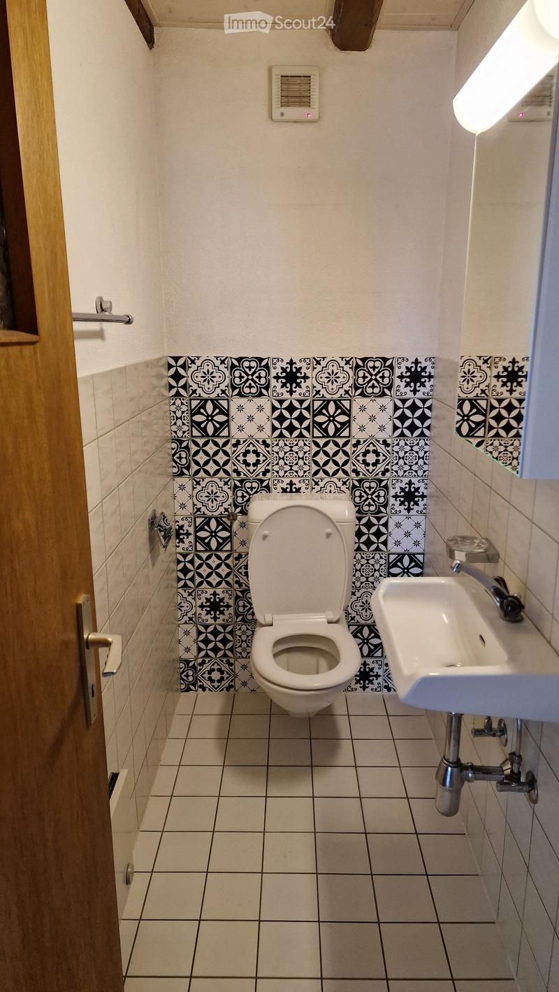 Modern bathroom with white tiles, black and white patterned wall tiles, a toilet, a sink, and a chrome faucet.