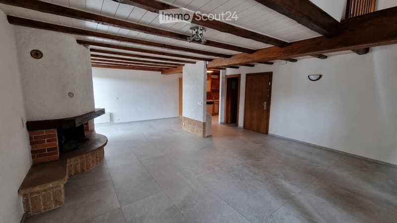 Empty room with exposed wooden beams, tiled floor, and a brick fireplace. No furniture or equipment present.