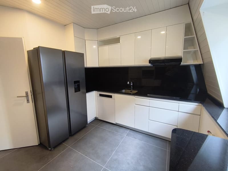 Modern kitchen with white cabinets, stainless steel appliances, and a black countertop.
