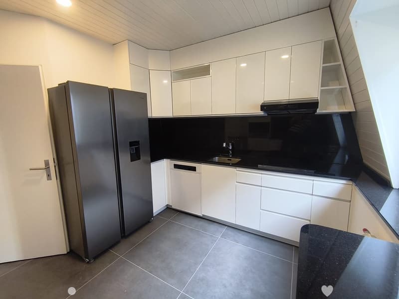 Modern kitchen with white cabinets, stainless steel appliances, and a black countertop.