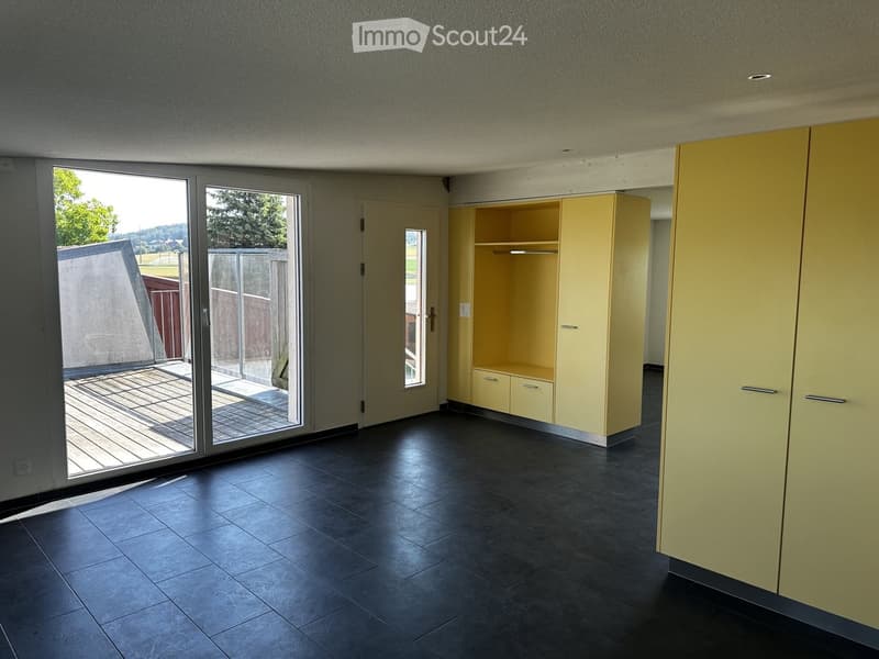 Empty room with dark tiled flooring, large sliding glass doors leading to a patio, and built-in yellow storage units.